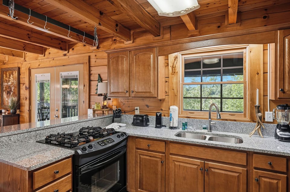 Cook your favorite meals in this fully equipped cabin kitchen with granite counters, gas stove, and forest views right outside your window.