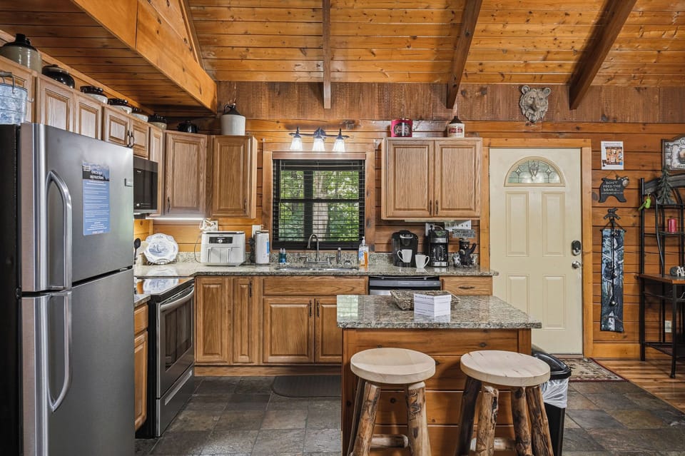 Step into your fully equipped cabin kitchen, where rich wood details and granite countertops set the stage for home-cooked meals. The cozy space blends rustic charm with modern appliances, making it easy to savor your getaway.