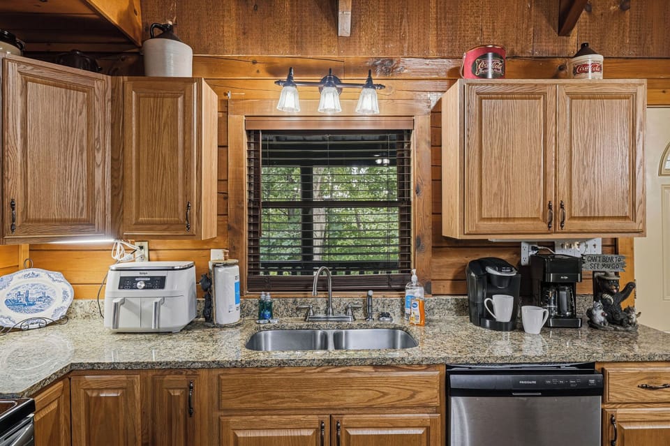 Step into a warm, cabin-style kitchen with natural wood accents and modern conveniences—your coffee station awaits while you enjoy peaceful views of the surrounding greenery.