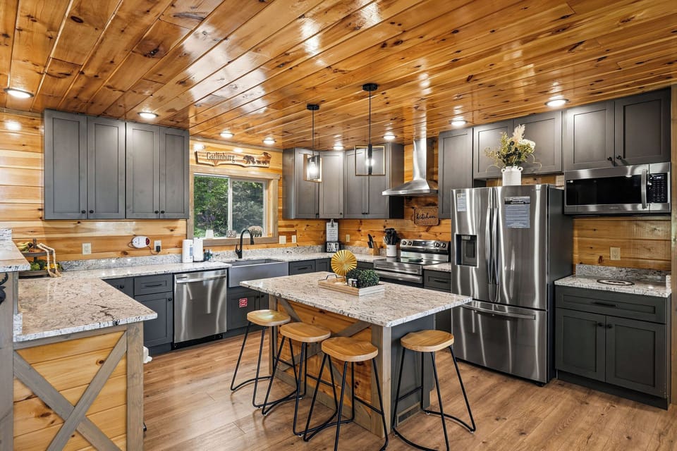 You'll love cooking in this stunning rustic kitchen with modern stainless steel appliances and granite countertops beneath warm wood ceilings.