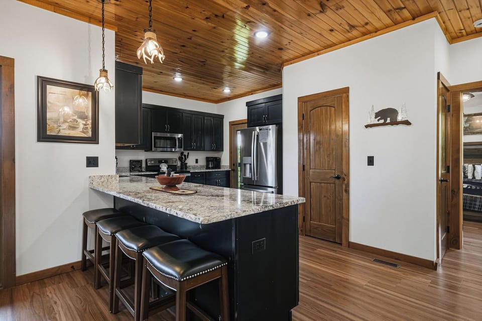 Gather around the island in your fully equipped kitchen, where granite countertops and stainless steel appliances set the stage for your mountain getaway meals. Warm wood ceilings and rustic touches create a cozy cabin atmosphere you'll love.