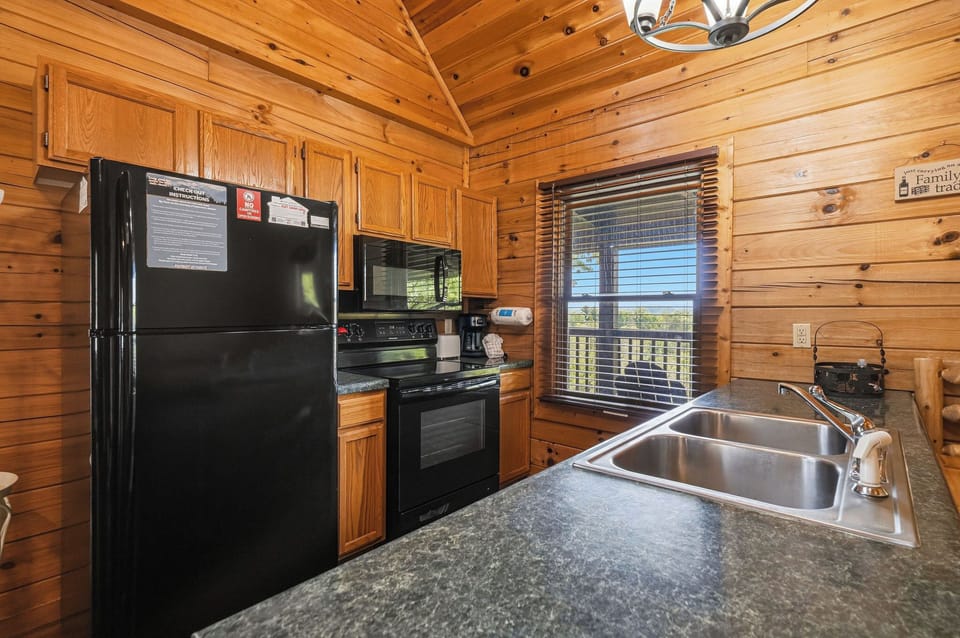 Your fully equipped kitchen makes meal prep a breeze, with granite counters, modern appliances, and a warm cabin ambiance framed by natural pine walls and vaulted ceilings.