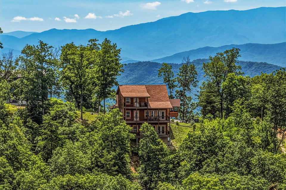 Mountain property nestled among lush greenery with stunning layered mountain ranges creating a dramatic backdrop for this elevated vacation retreat.