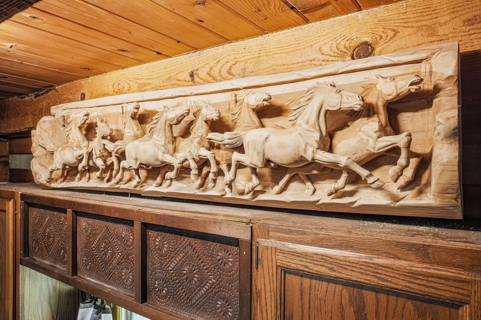 Admire this stunning hand-carved relief of wild horses in mid-gallop, bringing timeless artistry and rustic charm to your mountain retreat.