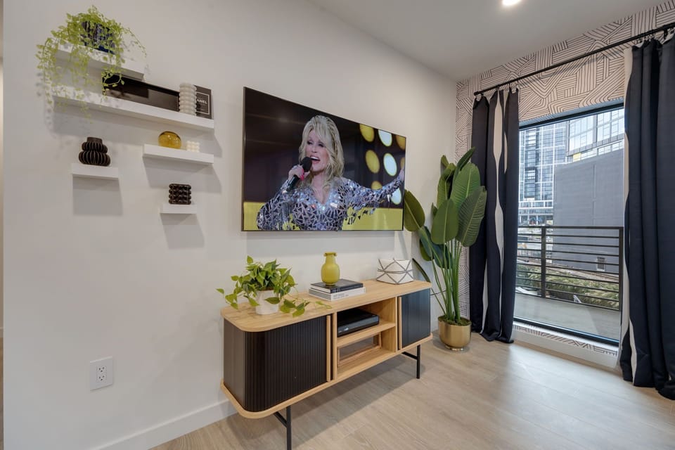 Bright open living space featuring SMART flat-screen TV, designer furnishings, and patio entrance with pool view.