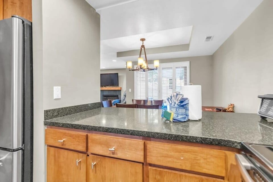 The view over the kitchen bar towards the dining area and living room. The kitchen bar features 2 bar stools for additional seating.