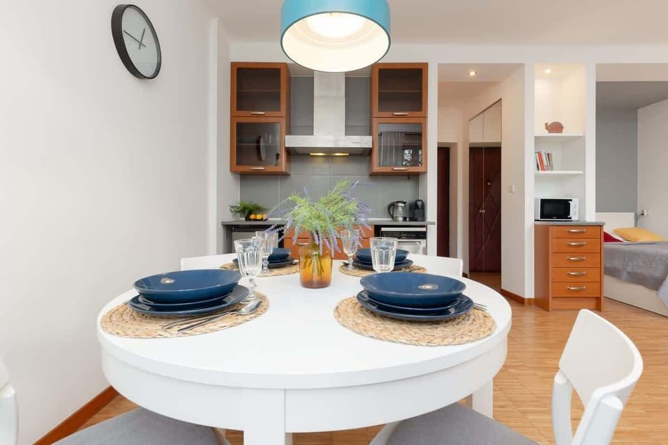 The dining zone viewed from another perspective, focusing on the white chairs and a pendant lamp above.

