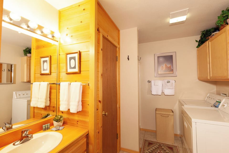 Your private bathroom features warm pine accents and fresh towels, with convenient in-unit laundry facilities just steps away for added comfort during your stay.