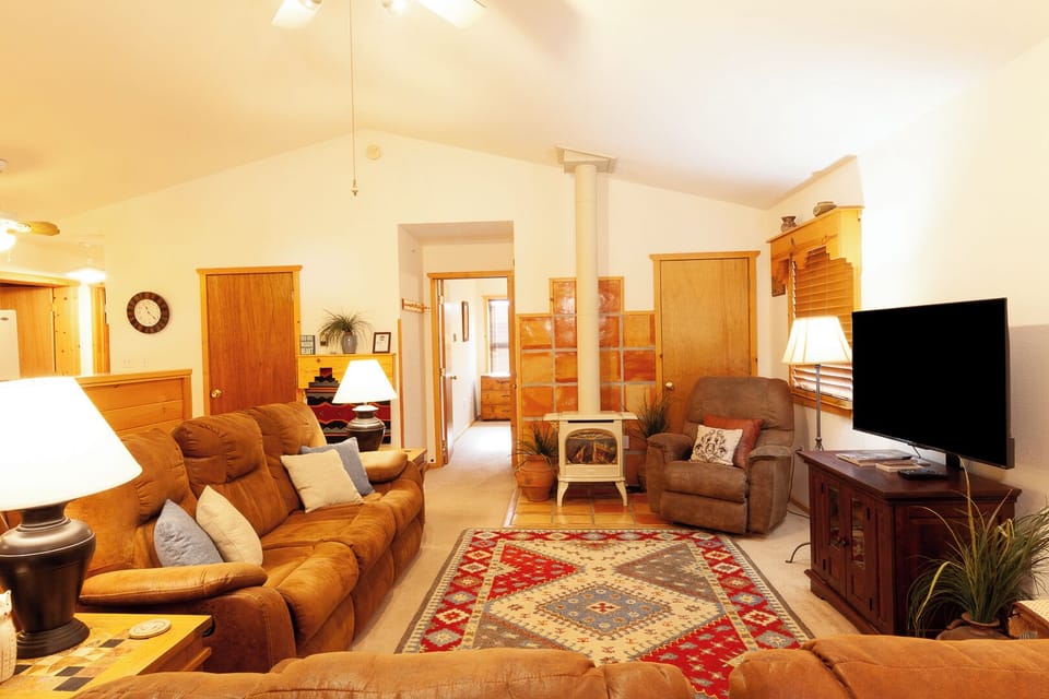 You'll love relaxing in this bright, spacious living room with vaulted ceilings, plush leather seating, and a charming wood stove that adds warmth and character.