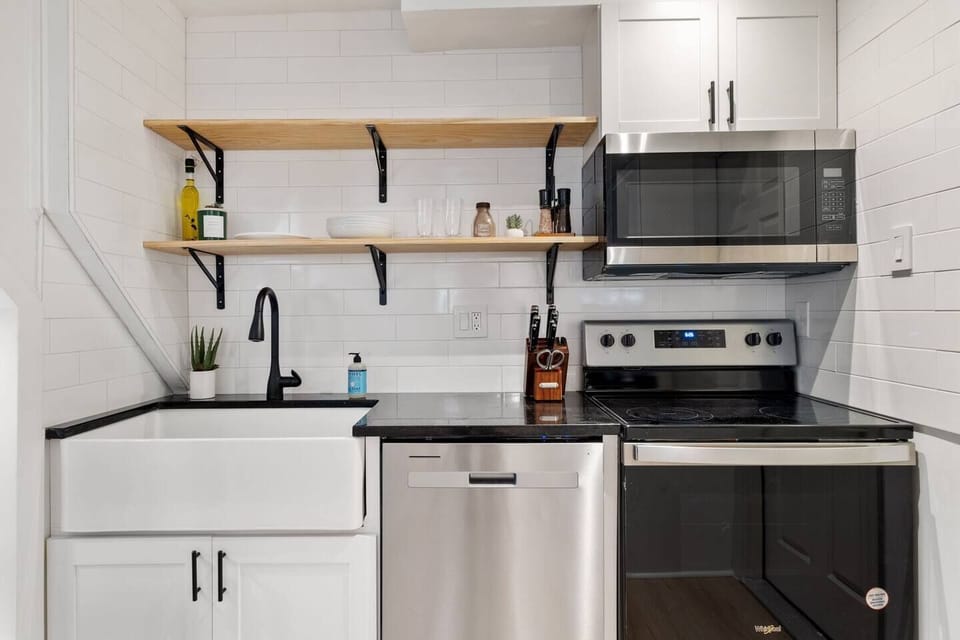 Kitchen featuring huge farmhouse sink, dishwasher, stove top, microwave, cooking accessories.