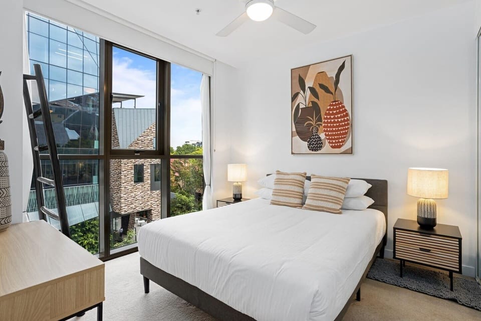 The primary bedroom highlights a queen-sized bed and gorgeous full-height glass windows.
