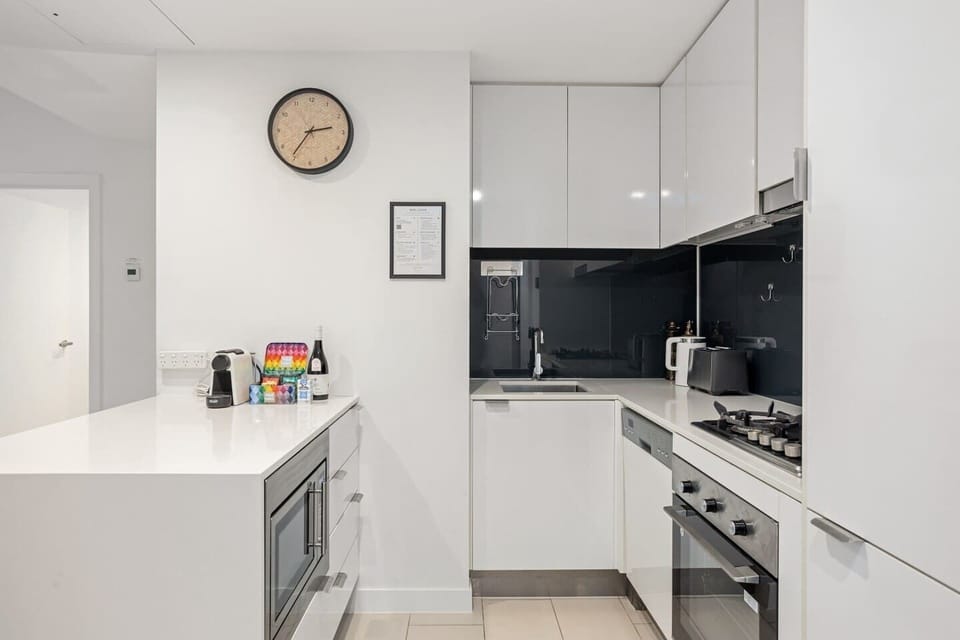 The sleek white kitchen comes fully equipped to prepare meals at home, with high-quality appliances and cooking utensils.
