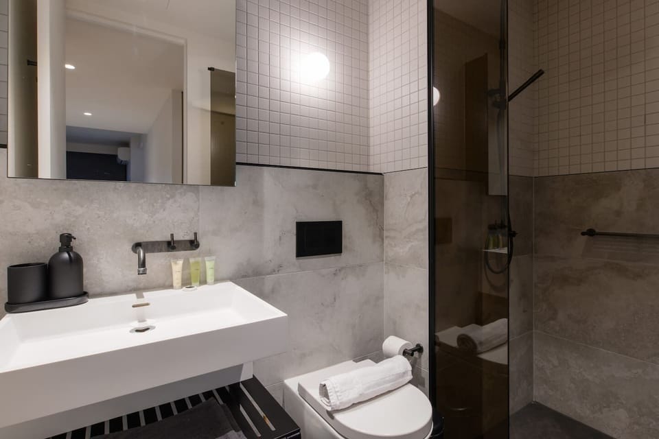 Both ensuite bathrooms feature modern walk-in overhead showers, sleek vanities, and complimentary toiletries for your stay.