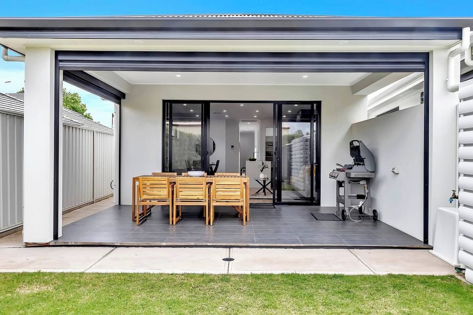 A spacious outdoor patio is complete with a BBQ and outdoor table setting for laidback afternoon cook-ups overlooking the private, grassy backyard.
