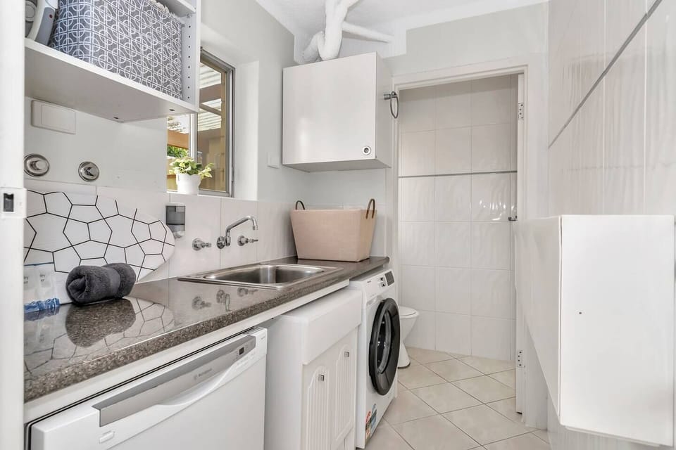 The laundry includes a basin and washing machine, while an adjoining powder room conveniently offers a second toilet.
