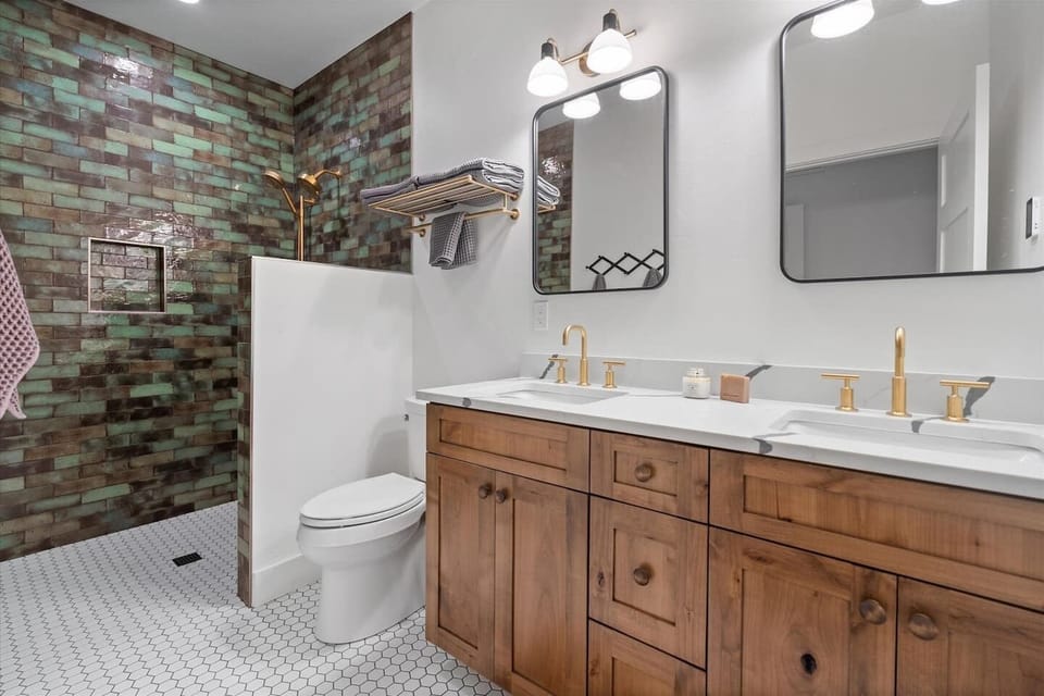 The focal point of the bathroom is the walk-in shower, enveloped in beautiful shades of green tile. The tiles, in varying hues of emerald, create a visually striking and calming effect.