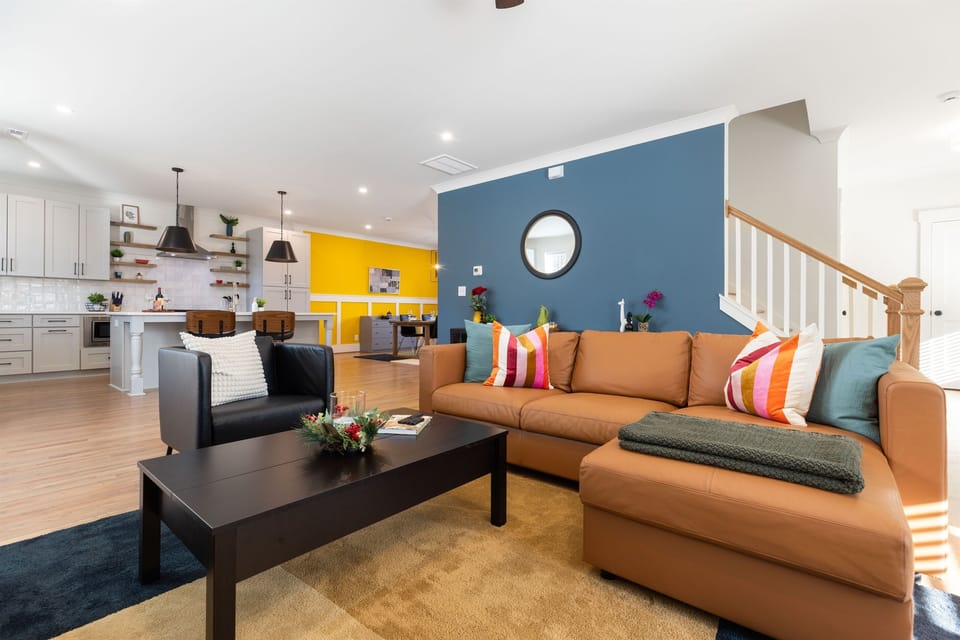 The vibrant and fun living room makes for a beautiful gather space. downstairs. The large home has an open floor plan, perfect for groups! The large leather couch and two seating chairs provide room for your group to gather.