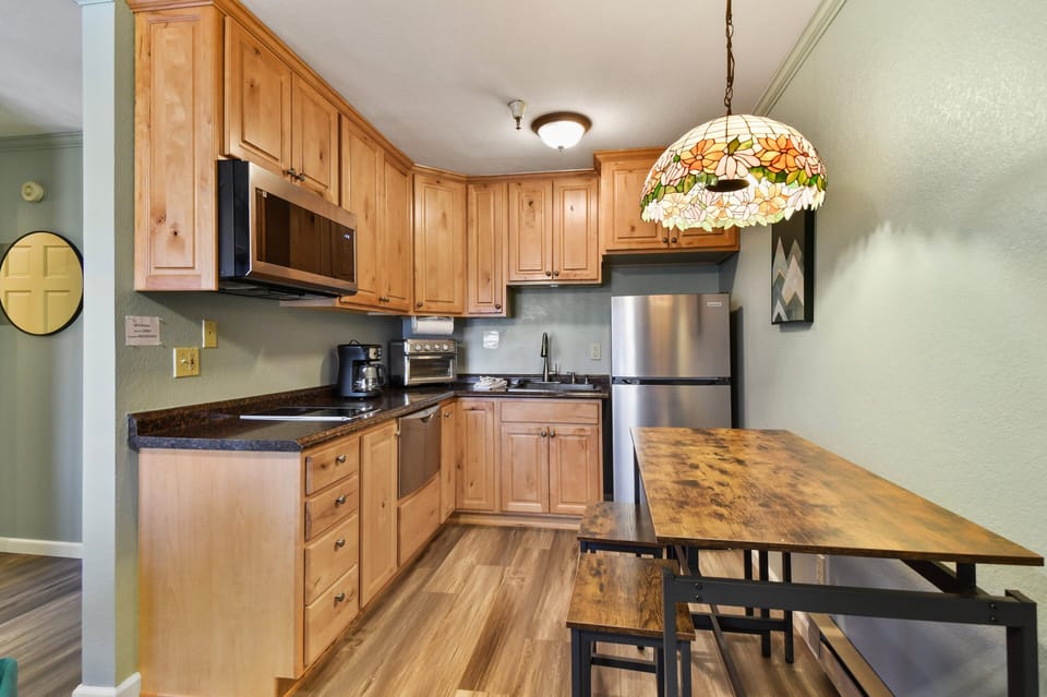 Fully equipped kitchen with stainless appliances, ample cabinetry, and dining table for meals or remote work.