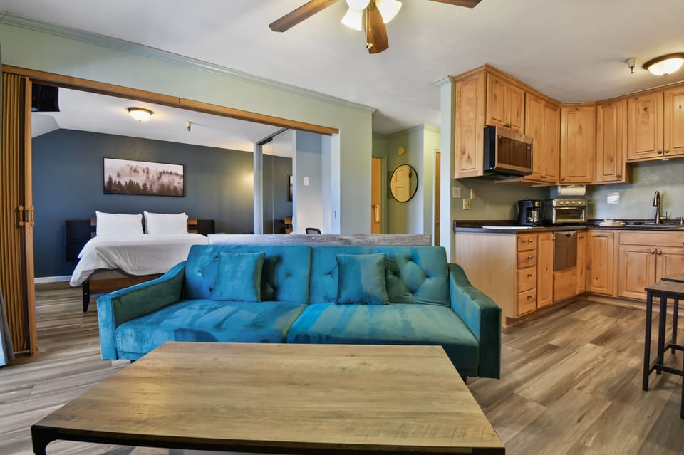 Open studio layout with a stylish living area, sofa seating, and a fully equipped kitchenette just steps from the bed.