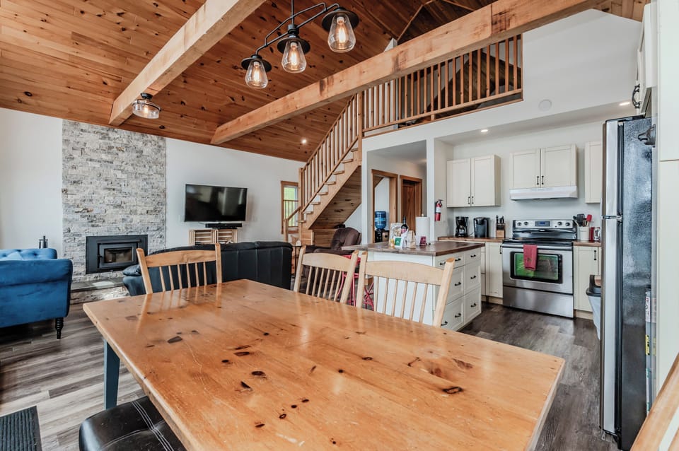 Open concept living means you are never far from the fun! The great room features high vaulted ceilings, a stone fireplace, and a cozy living area. The open-plan kitchen is fully equipped with modern appliances and a large island.