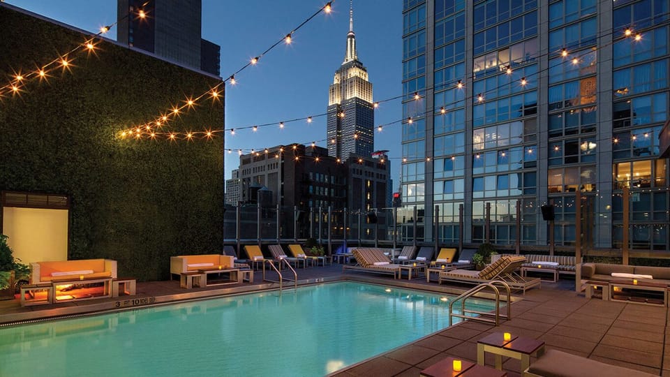 Unwind poolside under string lights with skyline views.