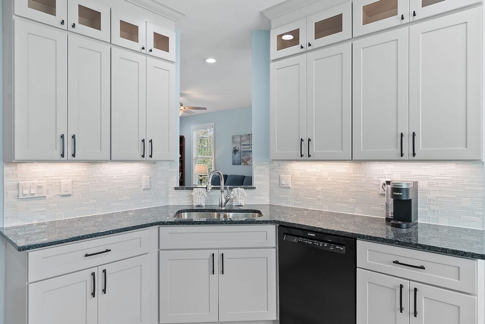 Prepare your favorite meals in this bright, fully-equipped kitchen featuring pristine white cabinetry, granite countertops, and modern appliances.
