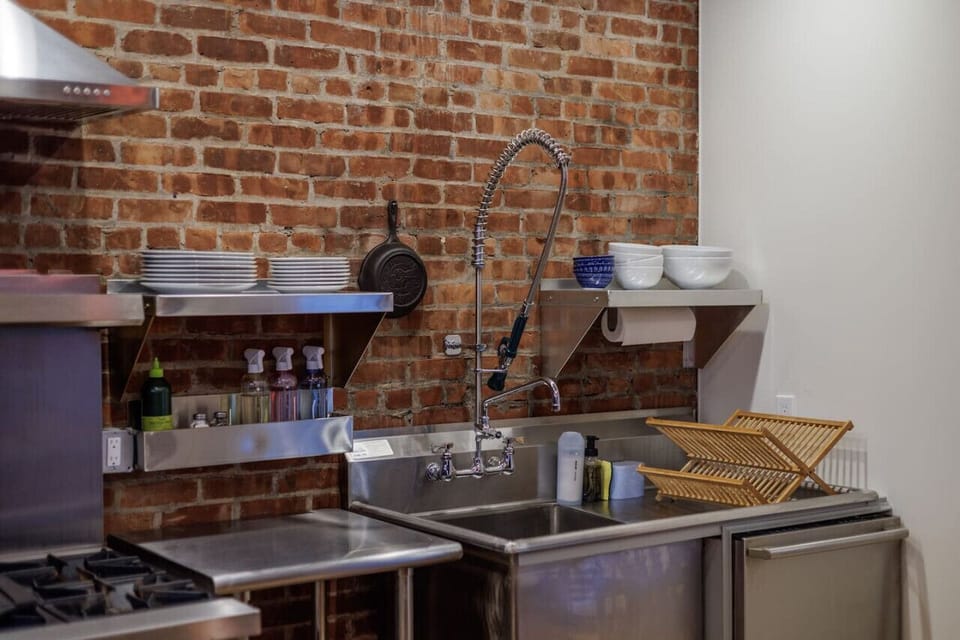 A well-equipped kitchen with stainless steel finishes, open shelving, and a deep industrial-style sink—perfect for cooking like a pro.