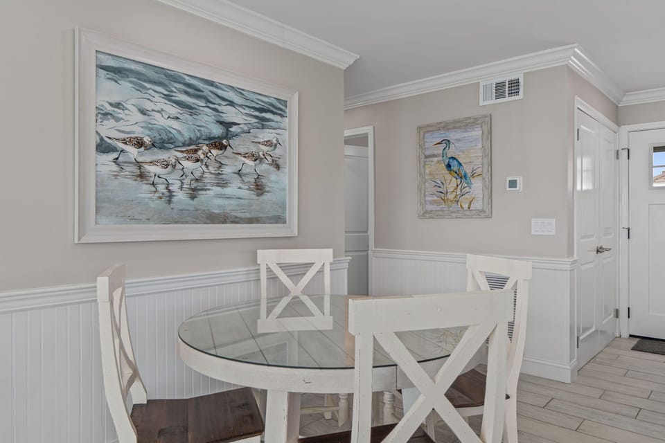 Your beachside dining spot features coastal artwork and crisp white furnishings, creating the perfect atmosphere for morning coffee or evening meals.
