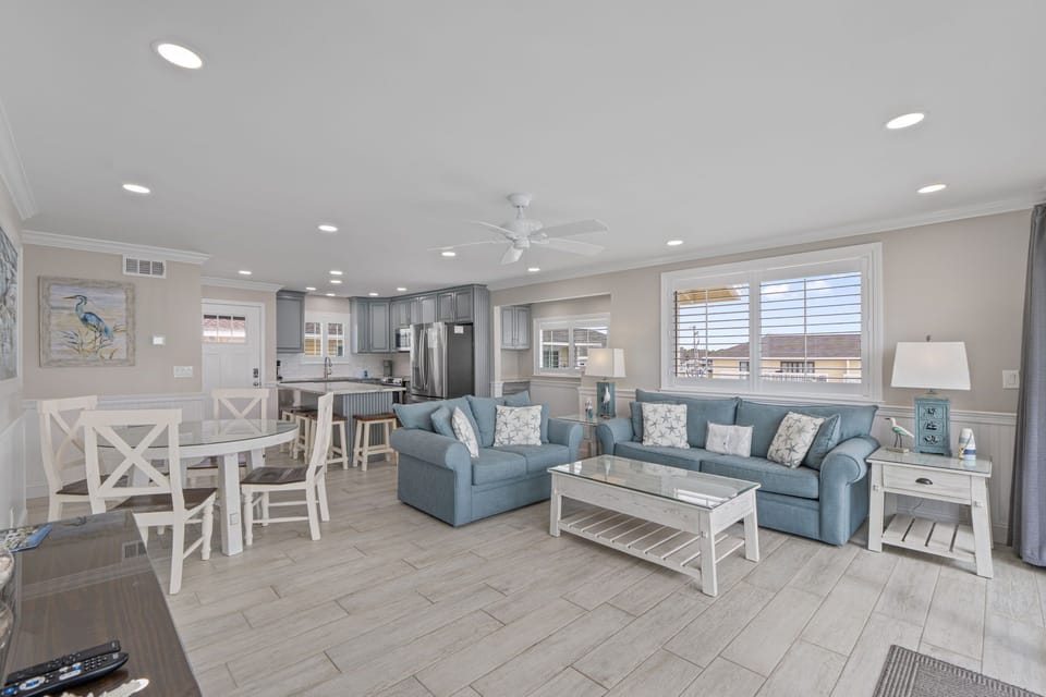 Relax in your bright, open living space with comfortable blue sectional seating, coastal decor, and a fully equipped kitchen perfect for home-cooked meals.