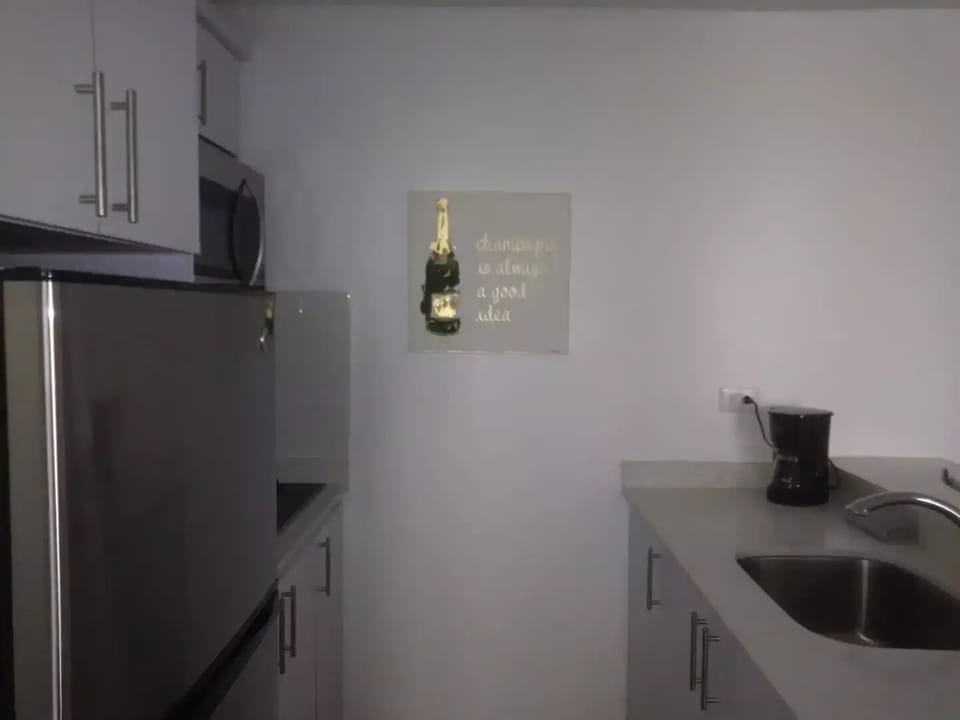 Fully equipped kitchen with stove, microwave, fridge, pots, pans, and utensils.