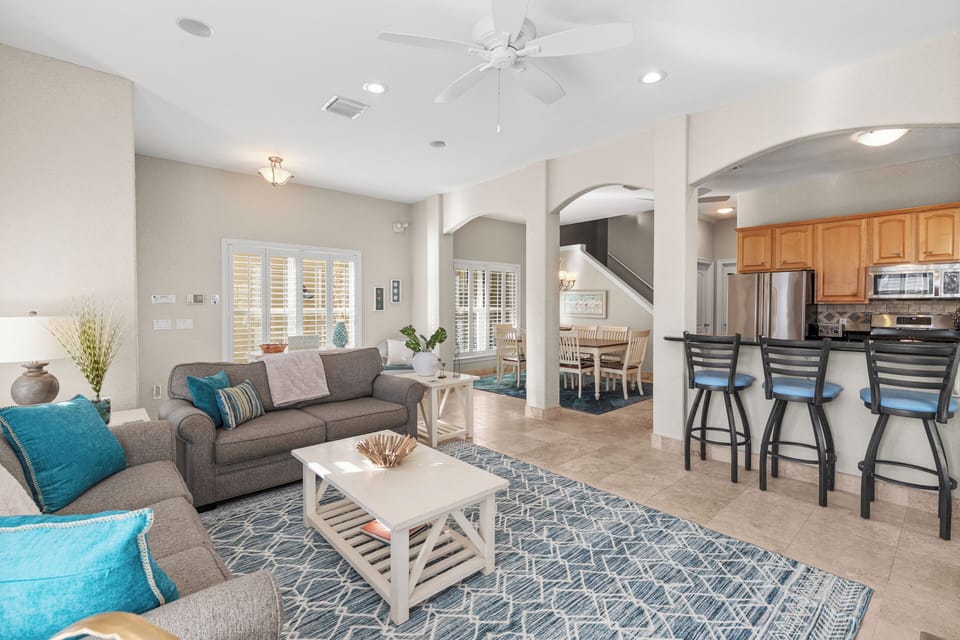 Your open-concept living space welcomes you with plush gray seating, vibrant turquoise accents, and modern kitchen perfect for memorable gatherings.