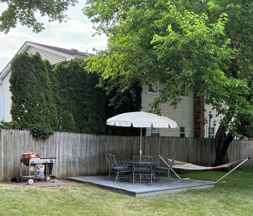 Large fenced in backyard with BBQ and canopy