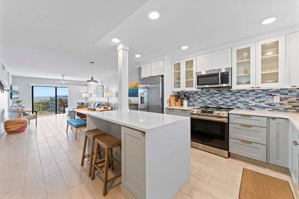 Open kitchen and living area, featuring modern appliances, bar seating, and a spacious layout.