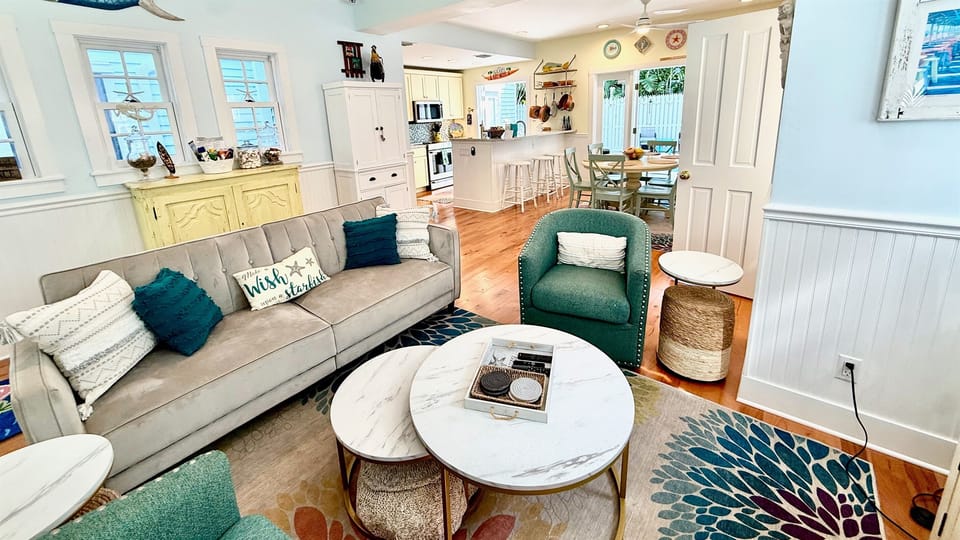 Unwind  in the bright living room, featuring a versatile futon sofa and two inviting chairs. Whether you're lounging with a book, enjoying movie nights, or simply taking in the ambiance, this comfortable arrangement is designed for relaxation.