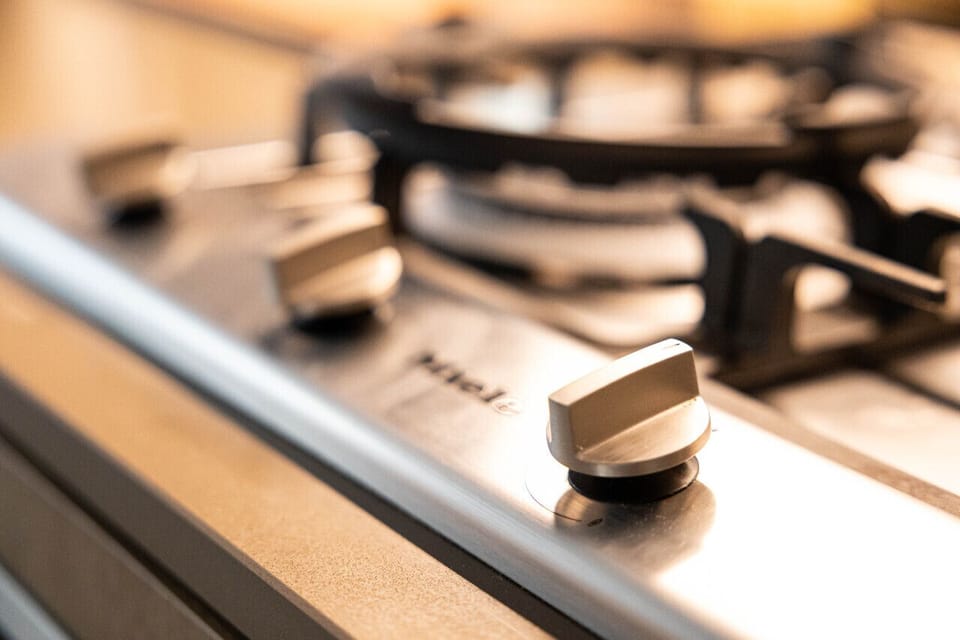 A close-up of the stainless steel Miele gas cooktop with solid metal knobs — a quality appliance for guests who enjoy cooking during their stay.