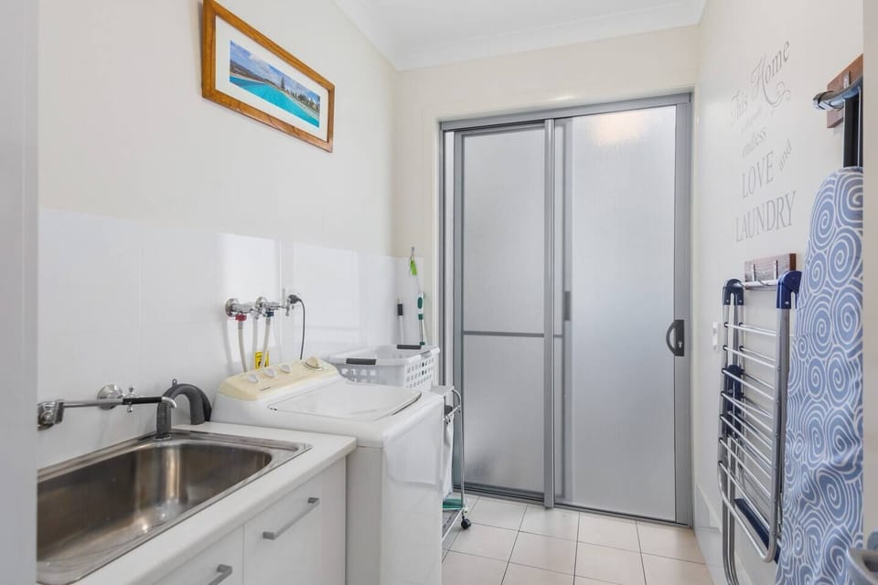 The laundry offers a washing machine and basin, while a clothesline is available in the backyard. 
