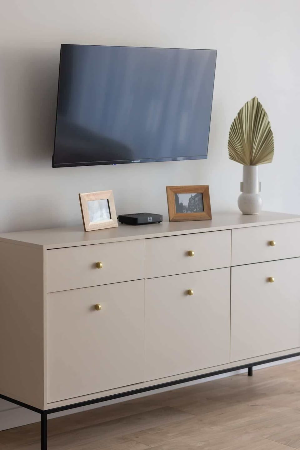 A minimalistic TV stand with a mounted flat-screen TV and decorative elements adding a cozy touch.
