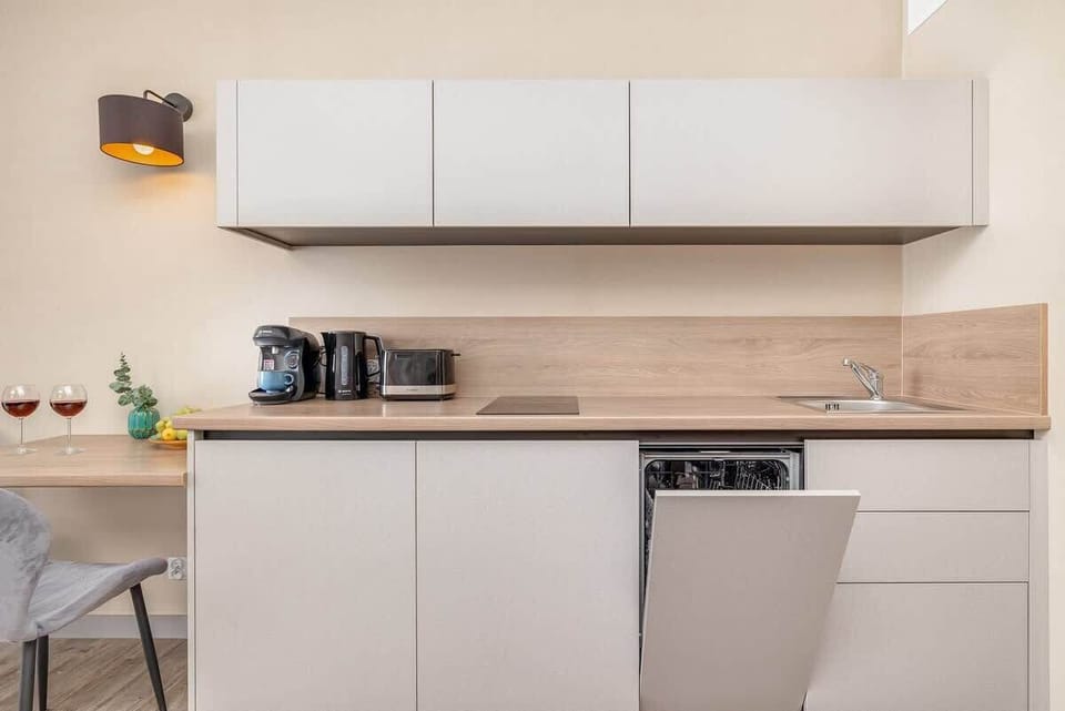 A small dining area with modern chairs, wall-mounted TV, and a light color scheme.

