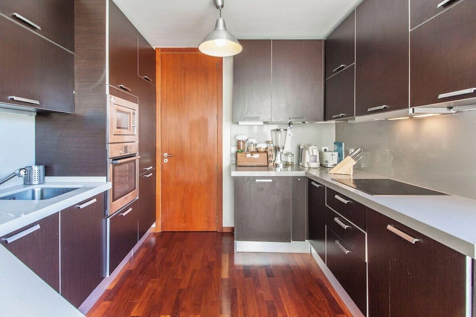 Modern kitchen with dark wood cabinetry and stainless steel appliances — Villa do Casalinho, luxury holiday villa in Sesimbra