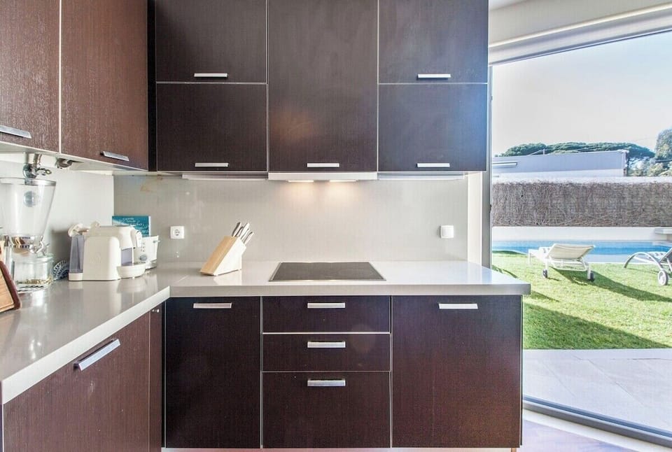 Modern kitchen with dark cabinetry and white countertops — Villa do Casalinho, luxury holiday villa in Sesimbra