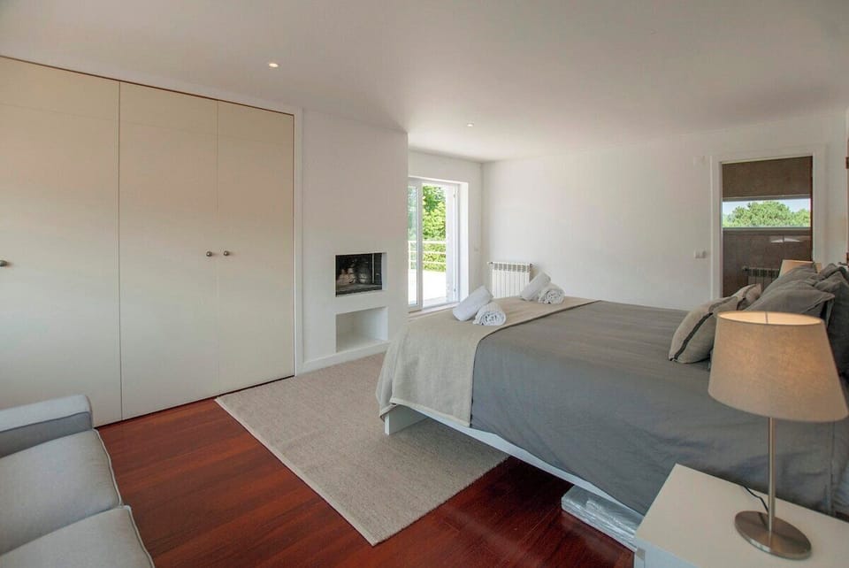 Spacious master bedroom with fireplace and glass doors — Villa Linda, luxury holiday villa in Sesimbra