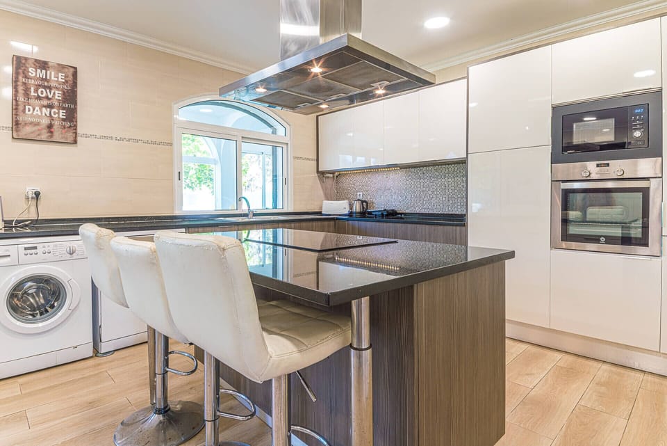 Modern kitchen with island seating and stainless steel appliances — Villa Buganvilia, luxury holiday villa in Aroeira