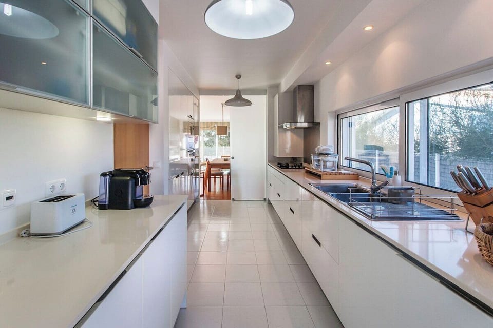 Modern galley kitchen with white cabinetry and stainless steel appliances — Villa Comporta, luxury holiday villa in Alcácer do Sal