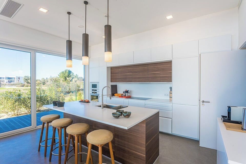 Modern open-plan kitchen with island seating and pendant lights — Villa Montchavin, luxury holiday villa in Sesimbra