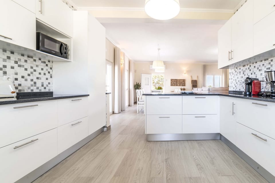 Modern open-plan kitchen with white cabinetry and dark countertops — Monte do Vale, holiday villa in Ferreira do Alentejo