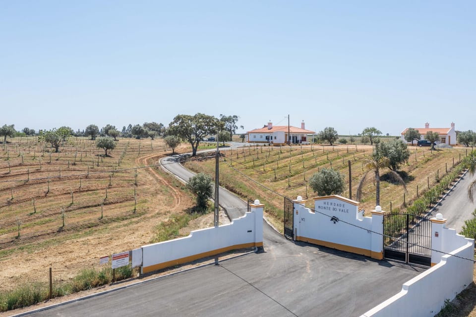 Gated entrance with white pillars and orange-tiled roofs — Monte do Vale, luxury holiday villa in Ferreira do Alentejo