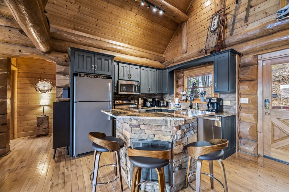 Enjoy casual meals or morning coffee at this inviting kitchen island with trendy bar seating, set against a backdrop of stone and smooth wood finishes.
