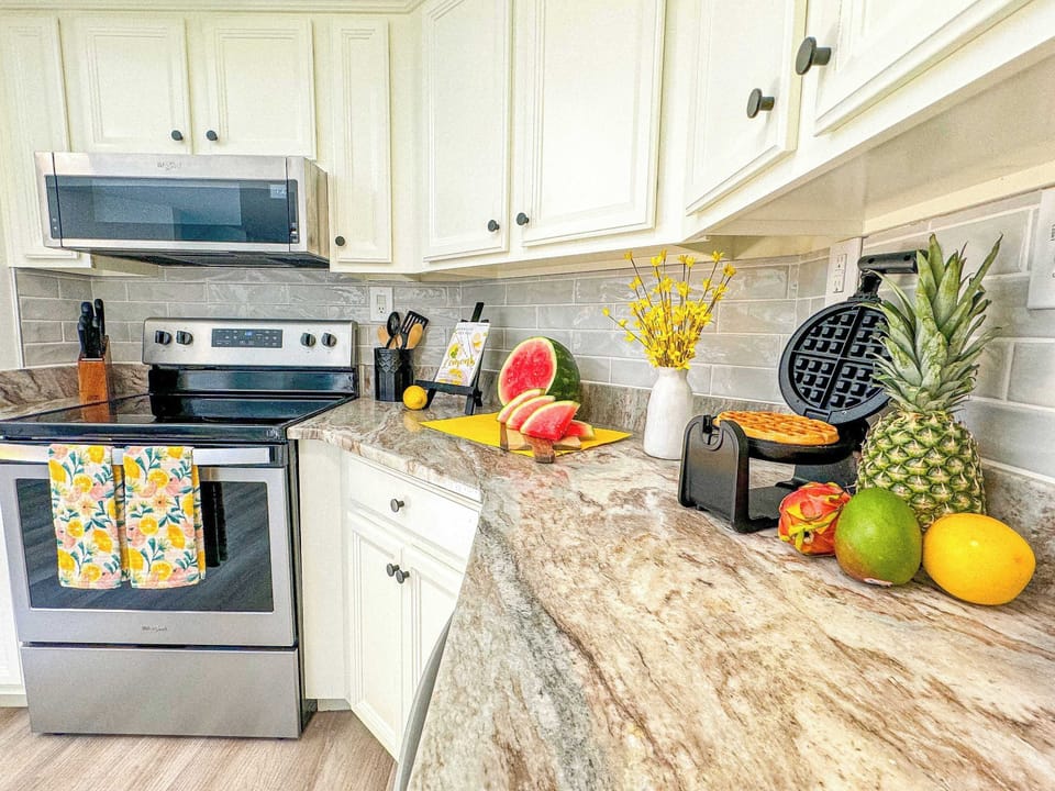 The clean, spacious kitchen offers beautiful granite countertops, a subway tile backsplash, and all stainless appliances.