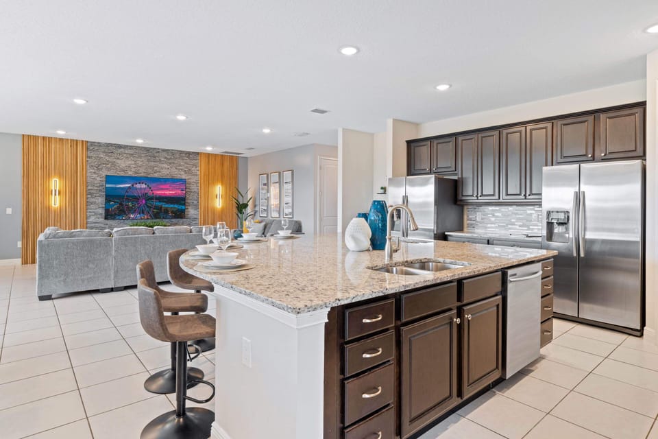 - Modern kitchen with granite countertops stainless appliances and island bar  
- Spacious open design connects to living area for family vacation gatherings  
- Orlando rental kitchen perfect for groups preparing meals near Disney parks