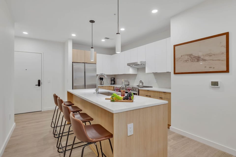 Fully equipped modern kitchen stocked with all culinary essentials and featuring brand new stainless steel appliances with an island offering bar seating.